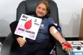 Donante de sangre posa con un rótulo de las vidas salvadas a raíz de la donación