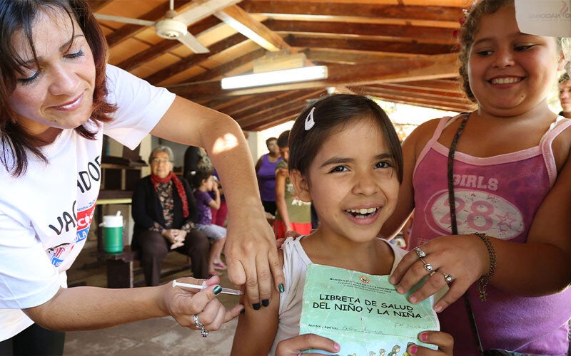 Niña siendo vacunada mostrando cartilla de vacunación