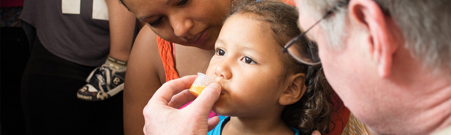 Enfermedades desatendidas, tropicales y transmitidas por vectores: niña bebiendo medicamento antiparasitario